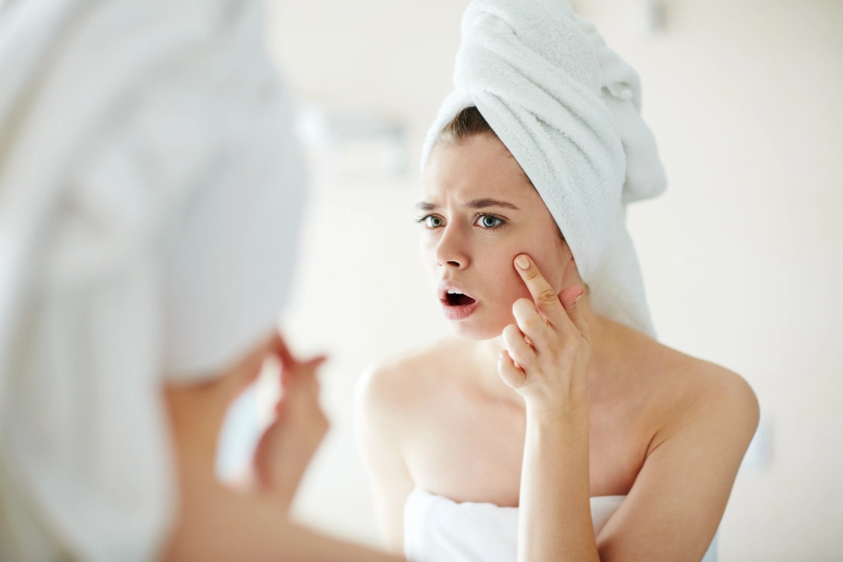 Woman checking her skin in a mirror after a laser treatment